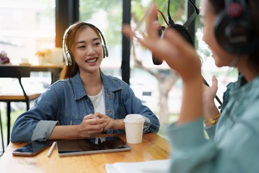 Asian podcaster making audio podcast working with guest at home studio.