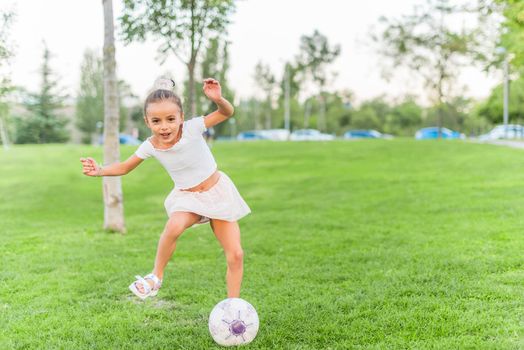 Front view of a little girl playing with soccer ball at park-