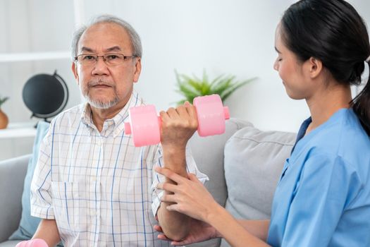 Unyielding senior patient doing physical therapy with the help of his caregiver. Senior physical therapy, physiotherapy treatment, nursing home for the elderly