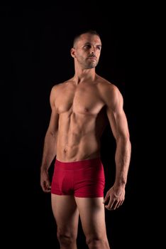 Athletic man in underwear. Mid shot. Black background.