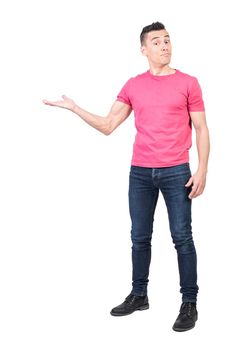 Full body of bewildered male model pointing aside with hand and looking at camera while standing isolated on white background in studio