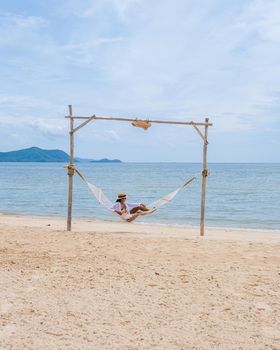 Women on the beach on a sunny day with a hammock on the beach in Pattaya Thailand Ban Amphur beach. Asian women on a tropical beach with palm trees and hammocks