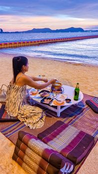 women bbq cooking noodle soup during sunset in Thailand Ban Amphur beach. relaxing with bbq Thai traditional on a tropical beach with palm trees and hammock during sunset