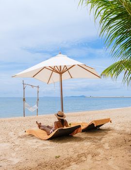 Women relaxing on a beach chair sunny day with a hammock on the beach in Pattaya Thailand Ban Amphur beach