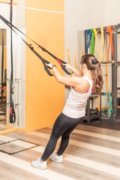 Athlete woman doing exercise with trx fitness straps in health club. Concept of trx exercises.