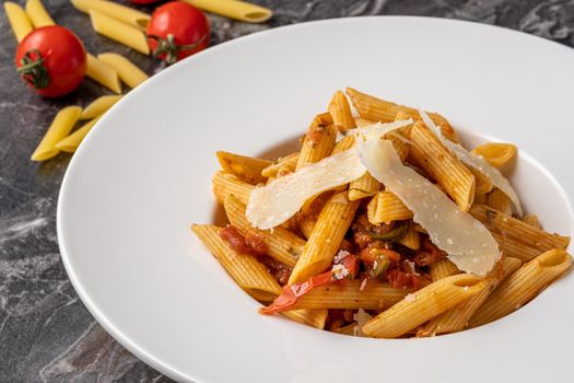 Penne pasta with a spicy sauce, chili pepper and grated parmesan cheese