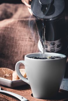 Pouring hot herbal tea into white mug