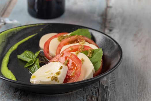 Fresh italian caprese salad with mozzarella and tomatoes on dark plate