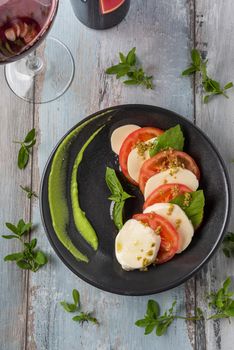 Fresh italian caprese salad with mozzarella and tomatoes on dark plate