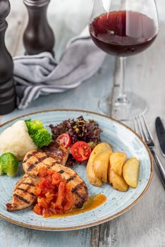 Grilled chicken breast in different variations with cherry tomatoes and different vegetables on wooden background