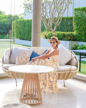 Asian women with a hat relaxing at the bar in a hotel during a luxury vacation. women by the bar during sunset