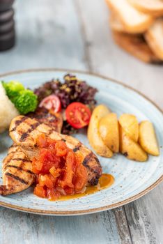 Grilled chicken breast in different variations with cherry tomatoes and different vegetables on wooden background