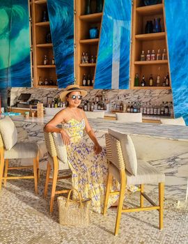 Asian women with a hat relaxing at the bar in a hotel during a luxury vacation. women by the bar during sunset