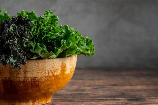green leafy kale vegetable in bamboo bowl on wooden table background