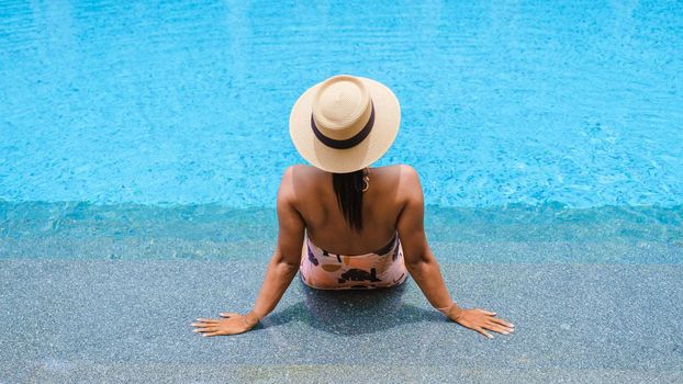 Asian women with hat relaxing in swimming pool, women swimming pool banner holiday vacation concept, Asian women in blue swimming pool luxury vacation