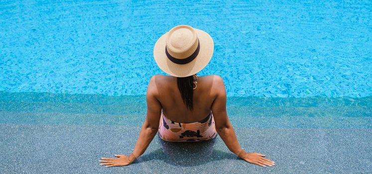 Asian women with hat relaxing in swimming pool, women swimming pool banner holiday vacation concept, Asian women in blue swimming pool luxury vacation
