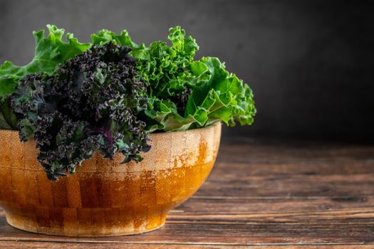 green leafy kale vegetable in bamboo bowl on wooden table background