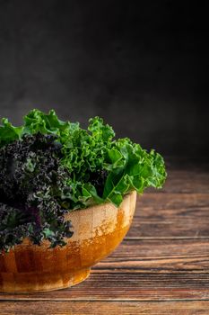 green leafy kale vegetable in bamboo bowl on wooden table background