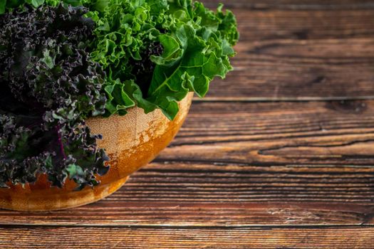 green leafy kale vegetable in bamboo bowl on wooden table background