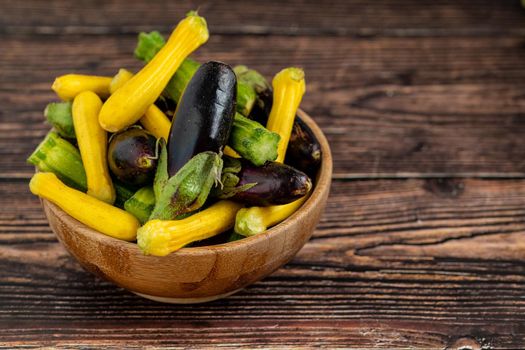 Baby Eggplant and zucchini in bamboo bowl on wooden table background