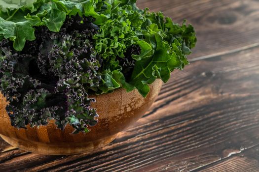 green leafy kale vegetable in bamboo bowl on wooden table background