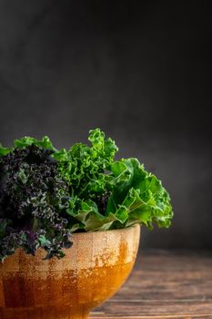 green leafy kale vegetable in bamboo bowl on wooden table background