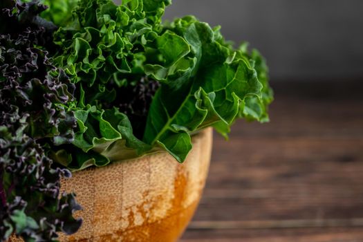 green leafy kale vegetable in bamboo bowl on wooden table background