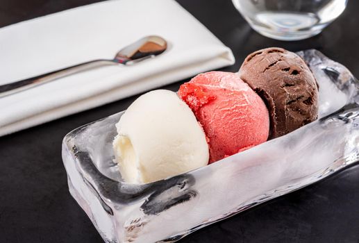 Strawberry and vanilla ice cream in ice bowl on black background.