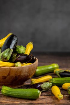 Baby Eggplant and zucchini in bamboo bowl on wooden table background