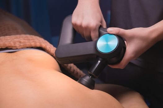 Therapist treats an athlete's chest injury with a massage gun, percussion massager.