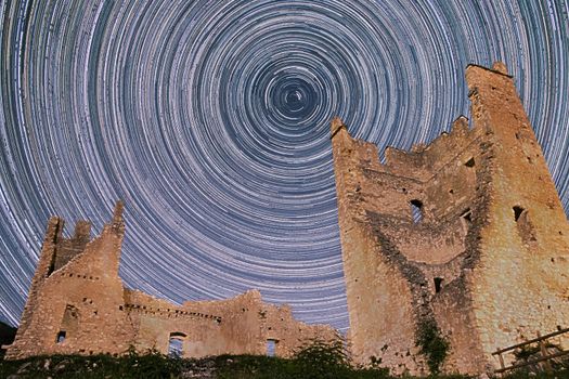 Night astrophotography of stars circling Chateau de Miglos, or d'Arquizat, a ruined castle in Miglos, Ariege, Occitanie, France. It is a listed national historic monument of France.