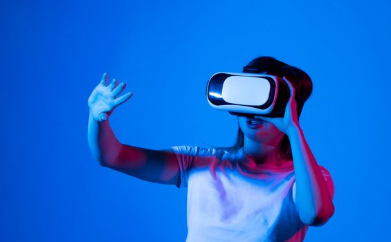 Woman in VR headset looking up and trying to touch objects in virtual reality. VR headset. Excited young woman in VR headset touching air during virtual reality experience at studio