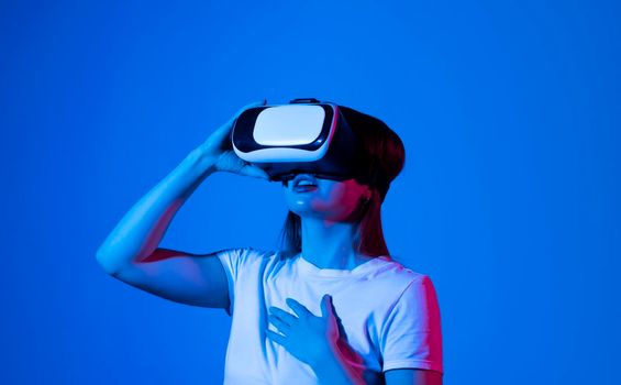 Young woman working in VR goggles on a grey background. Modern architect using virtual reality glasses at workplace. Designer working in augmented reality vr studio