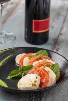 Fresh italian caprese salad with mozzarella and tomatoes on dark plate