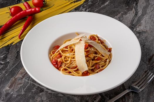 Spaghetti with a spicy sauce, chili pepper and grated parmesan cheese