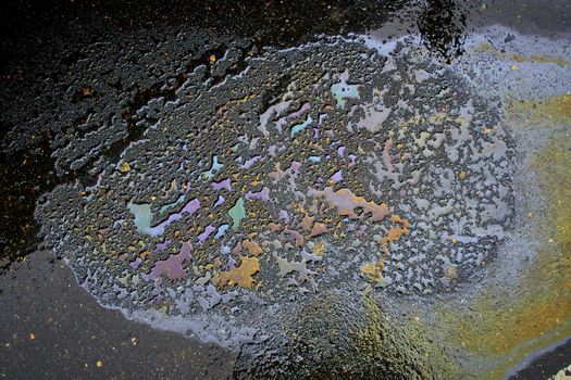 Gasoline spill on asphalt with a white dividing strip in a car park as a texture or background.