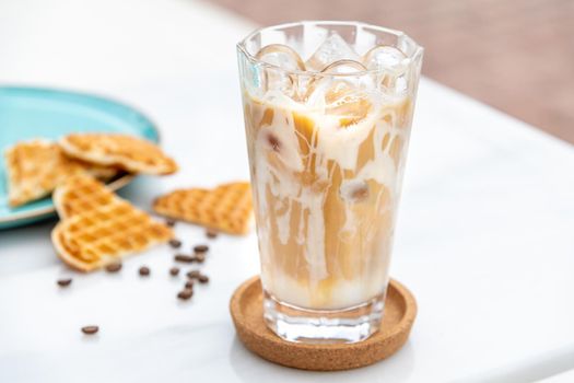 Iced caramel latte coffee in a tall glass with caramel syrup