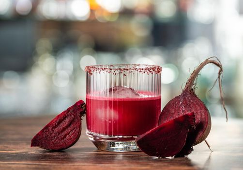 Alcoholic beetroot cocktail beverage in elegant glass on wooden table.