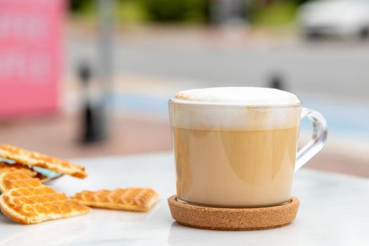 Cafe latte and heart waffles on marble table in the garden of the cafe