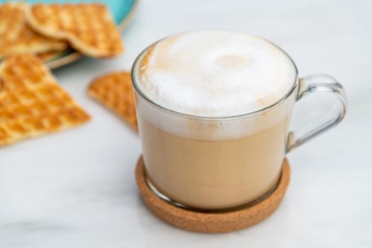 Cafe latte and heart waffles on marble table in the garden of the cafe