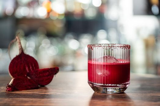 Alcoholic beetroot cocktail beverage in elegant glass on wooden table.