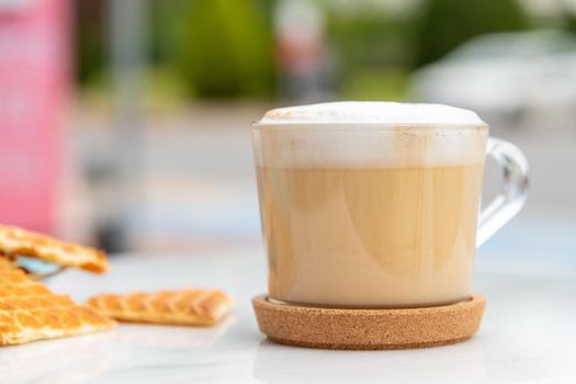 Cafe latte and heart waffles on marble table in the garden of the cafe