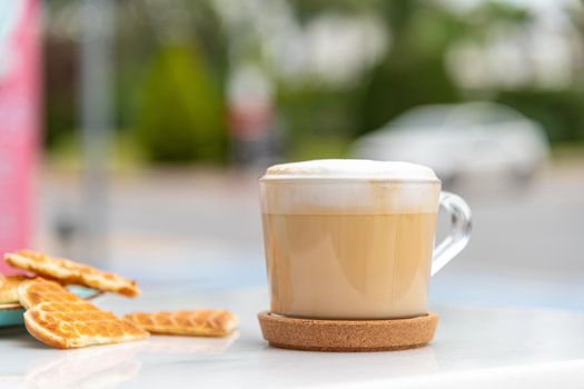 Cafe latte and heart waffles on marble table in the garden of the cafe