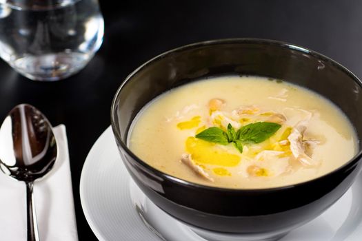 Creamy chicken soup on a black plate on a dark background.