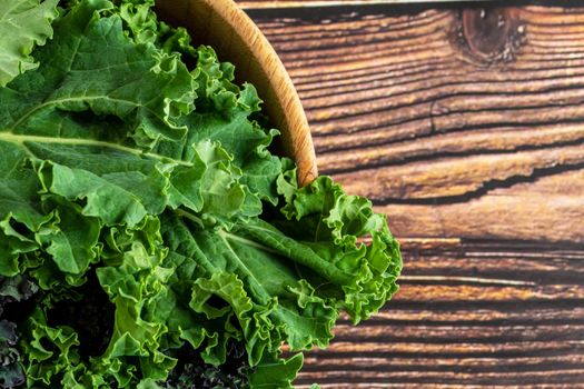 green leafy kale vegetable in bamboo bowl on wooden table background