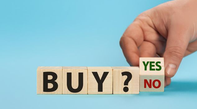 Time to buy. Hand turns a cube and changes the words buy no to buy yes. Business concept. Copy space