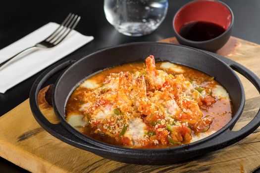 Shrimp casserole with tomatoes and peppers in a black stone pan.