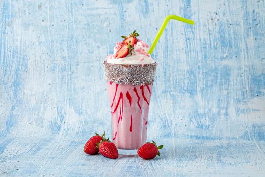 Refreshing strawberry milkshake on blue stone background