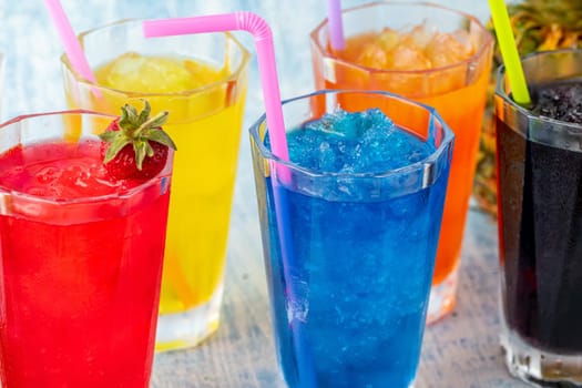 Refreshing frozens in various fruits and colors on a blue background.