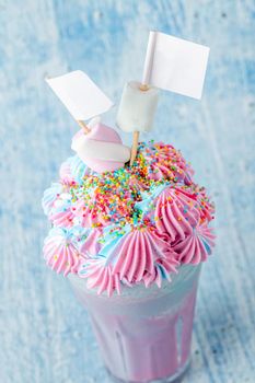 Blue and pink milkshake decorated with marshmallows on a blue background.